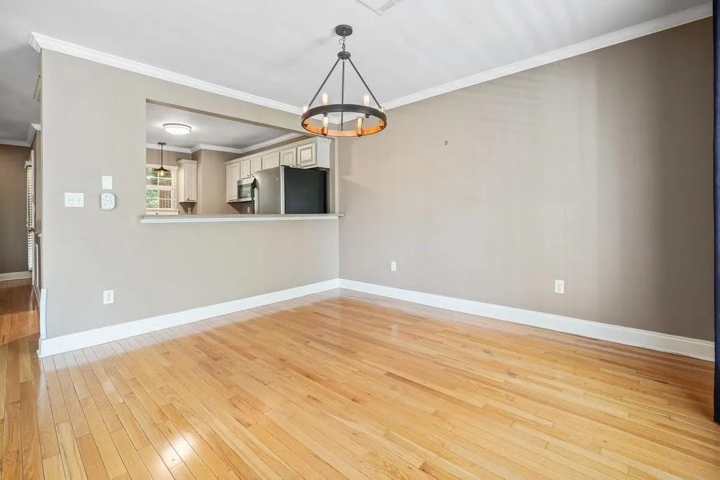 Empty room featuring light wood-type flooring, a chandelier, and ornamental molding