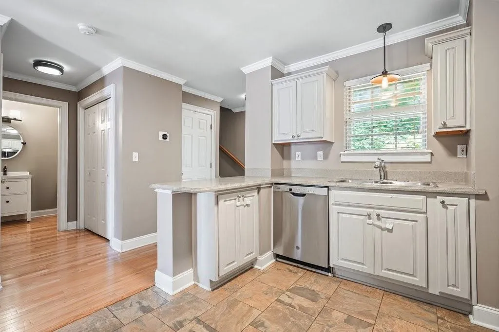 Kitchen featuring stainless steel dishwasher, light hardwood / wood-style flooring, sink, pendant lighting, and ornamental molding