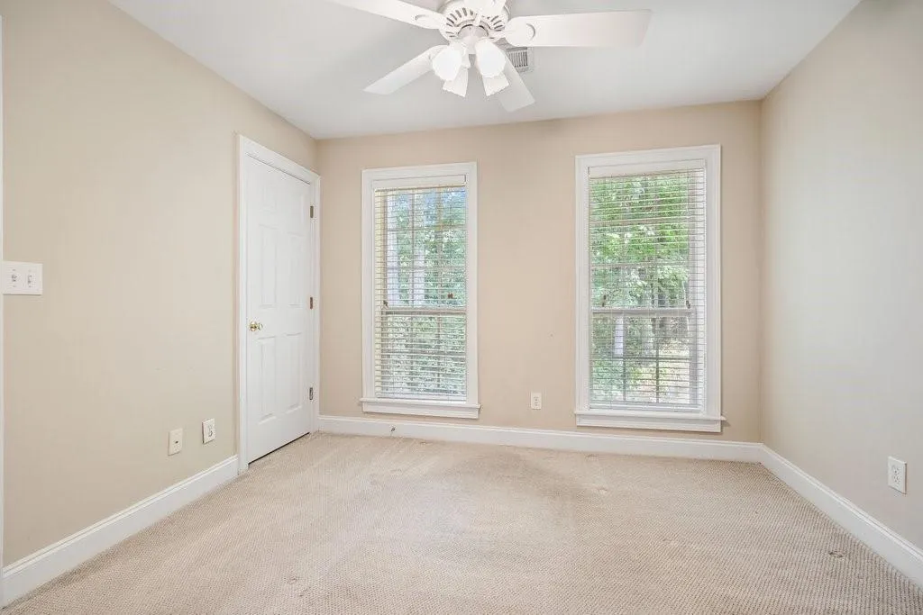 Empty room featuring light colored carpet and ceiling fan