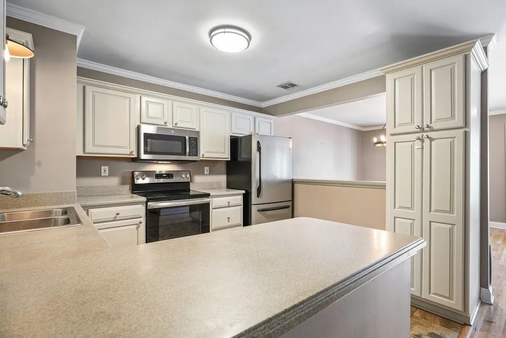 Kitchen featuring ornamental molding, light hardwood / wood-style floors, stainless steel appliances, and sink