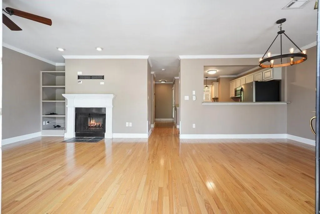 Unfurnished living room featuring ceiling fan with notable chandelier, crown molding, and light wood-type flooring