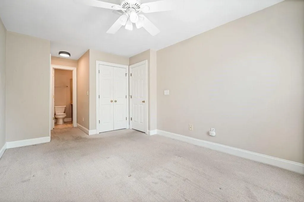 Unfurnished bedroom featuring ceiling fan, carpet flooring, and ensuite bathroom
