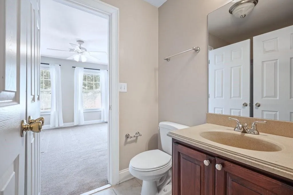 Bathroom with oversized vanity, ceiling fan, toilet, and tile flooring