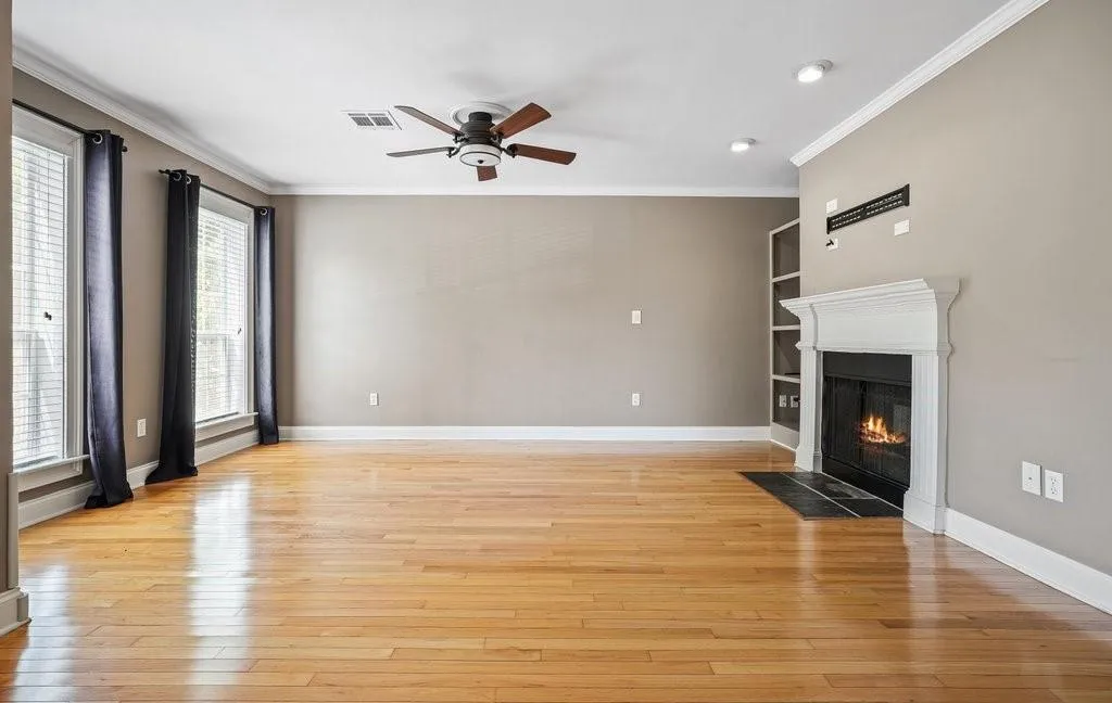 Unfurnished living room featuring ceiling fan, light hardwood / wood-style floors, and crown molding