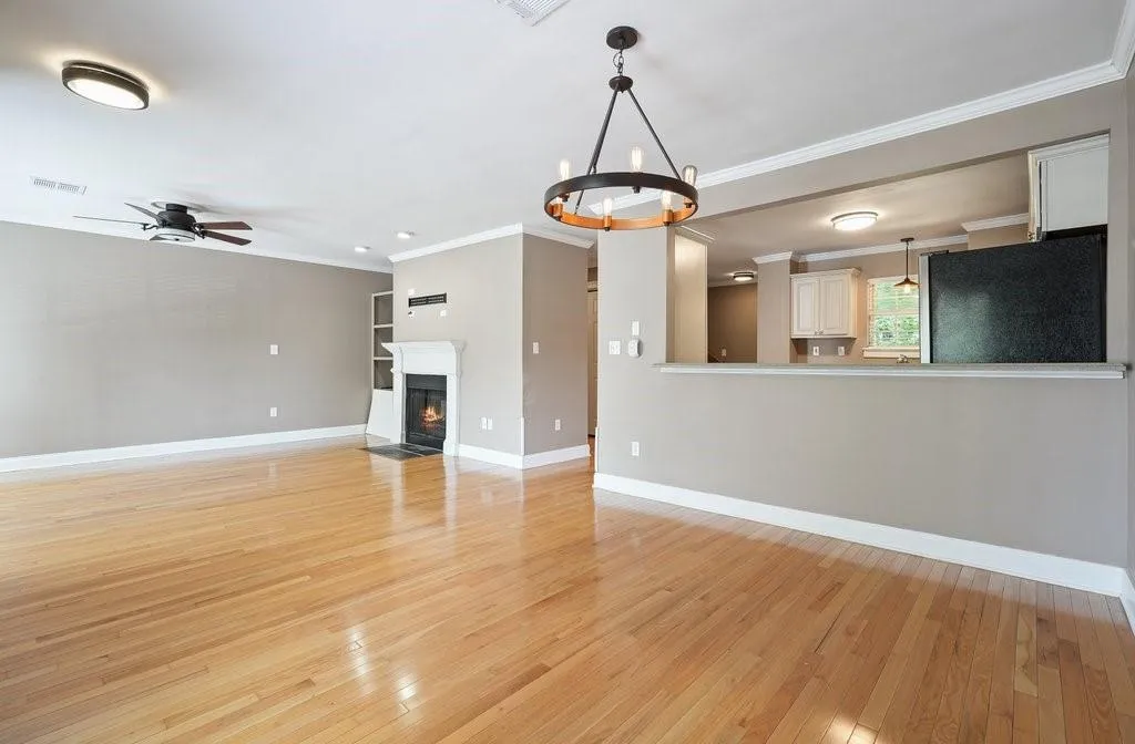 Unfurnished living room featuring ceiling fan with notable chandelier, light wood-type flooring, and crown molding