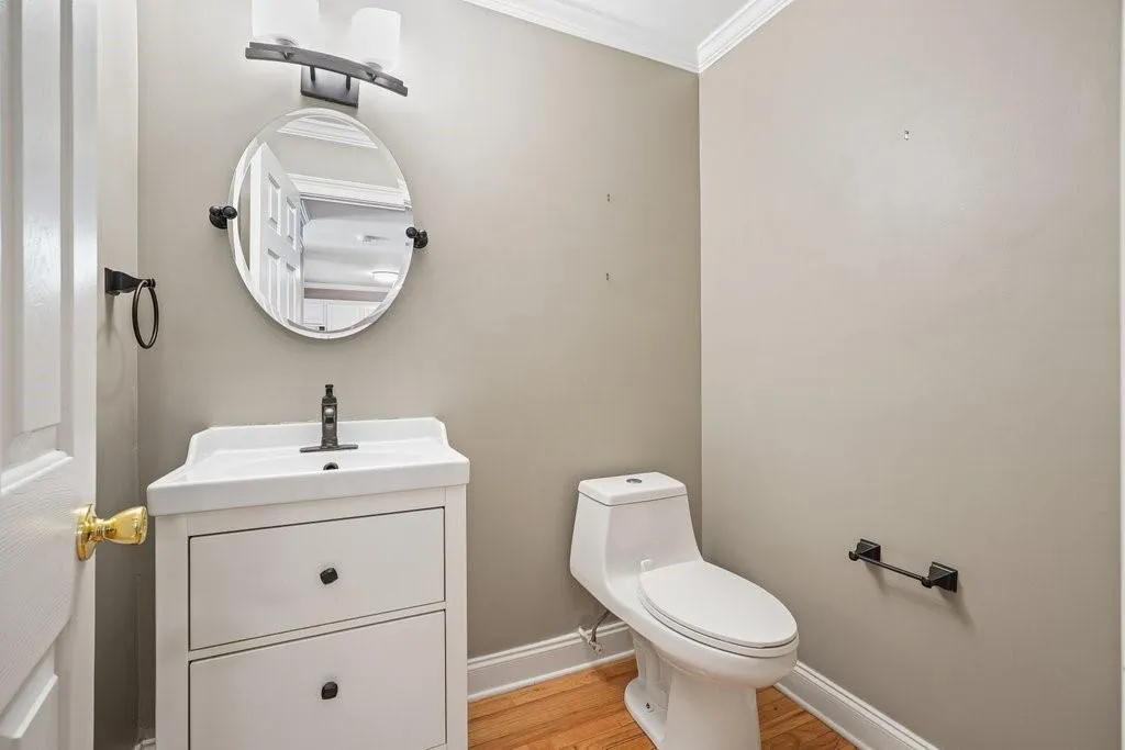 Bathroom featuring wood-type flooring, vanity, toilet, and crown molding