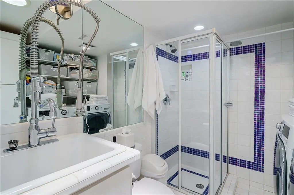 Full bath with vanity, a shower stall, recessed lighting, and tile walls