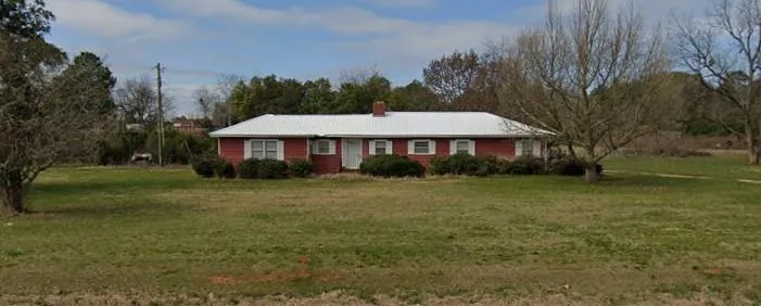 Brick exterior with a metal roof, white trim, and a prominent chimney