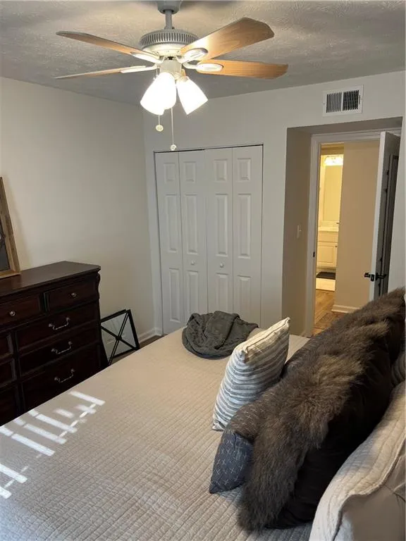 Bedroom with a textured ceiling, a closet, and ceiling fan