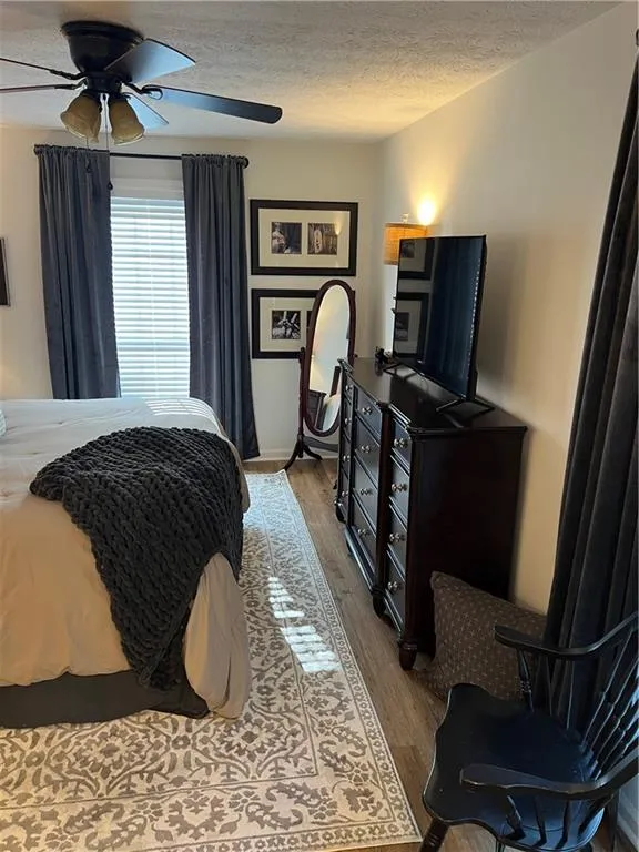 Bedroom with wood finished floors, a textured ceiling, and a ceiling fan
