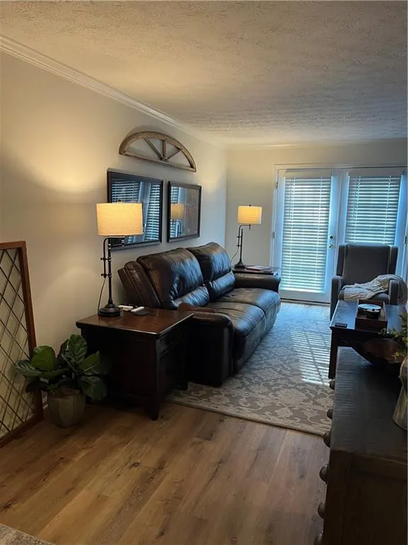 Living area featuring a textured ceiling, crown molding, and wood finished floors