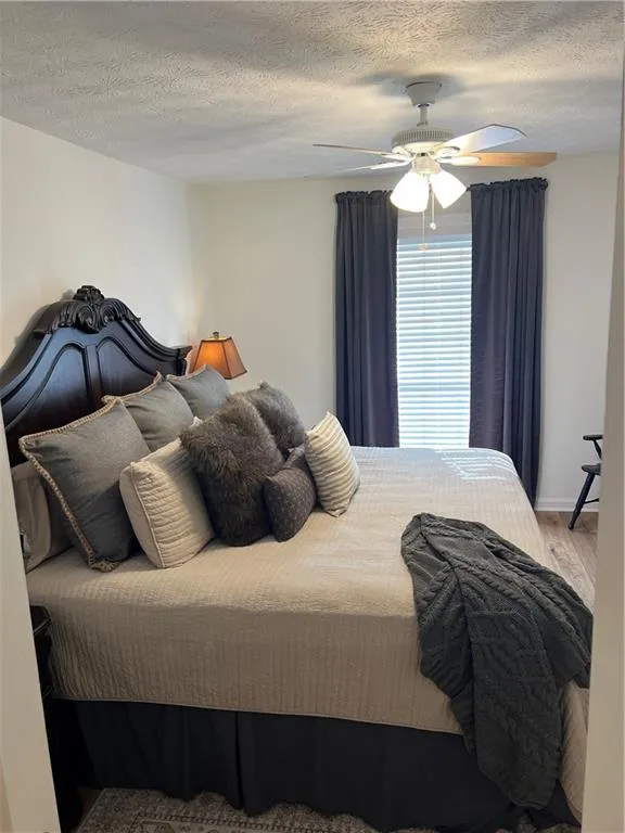 Bedroom featuring a textured ceiling, a ceiling fan, and wood finished floors