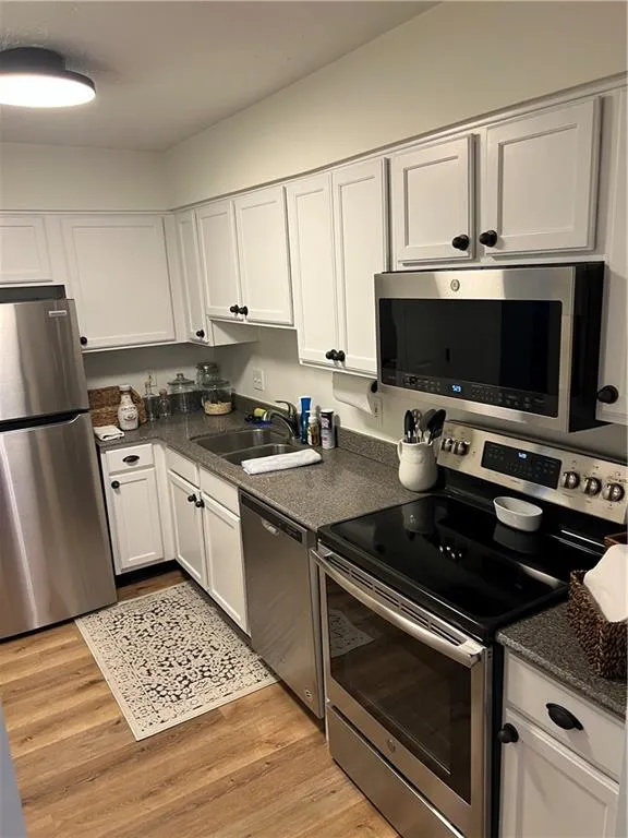Kitchen featuring appliances with stainless steel finishes, white cabinetry, and light wood finished floors