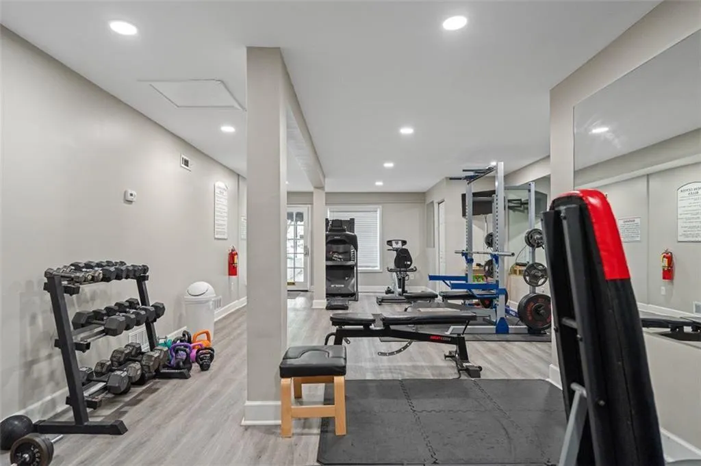 Exercise area with light wood-style floors and recessed lighting