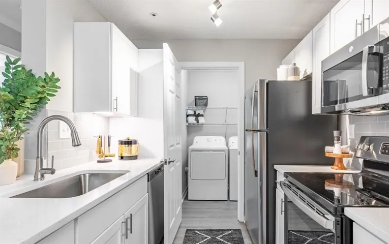 Kitchen with tasteful backsplash, light hardwood / wood-style flooring, appliances with stainless steel finishes, and sink