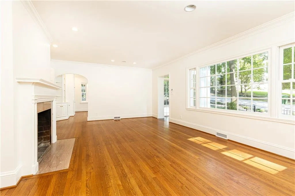 Spacious living room with wood burning fireplace and beautiful hardwood floors throughout.