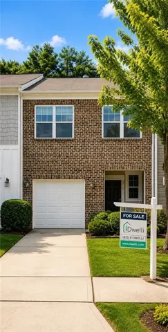 Two-story brick facade residence featuring a white garage door, concrete driveway, and front entryway