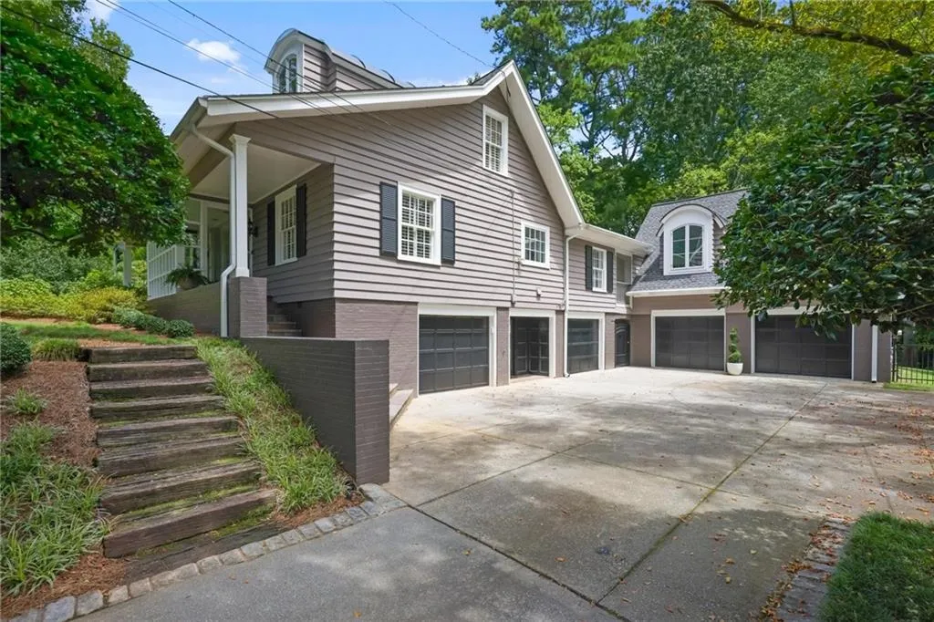 View of side of home with a garage, concrete driveway, stairs, and a porch