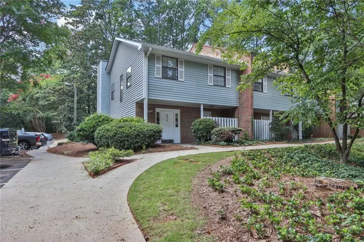 Siding exterior with white trim, brick accents, and a concrete pathway