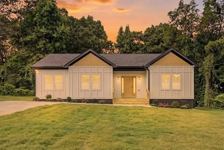 Modern ranch-style home featuring a dark shingle roof, white board-and-batten siding with dark trim, and a prominent front entry with a light wood door
