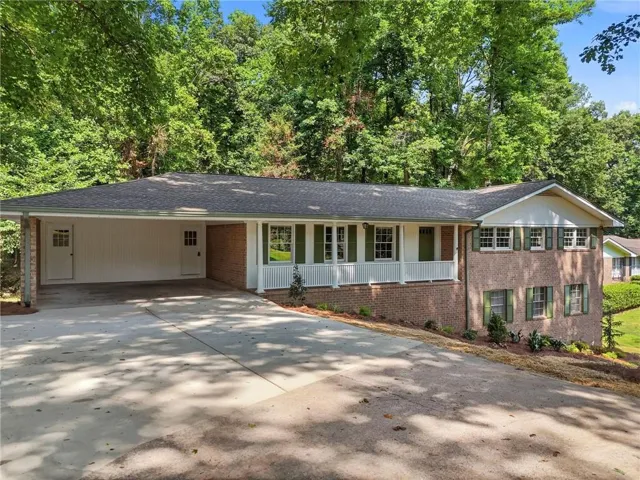 Brick and siding exterior with a front porch, green shutters, and a carport