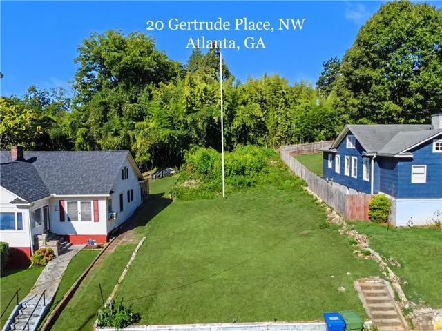 Expansive green lot featuring mature trees and a sloped terrain