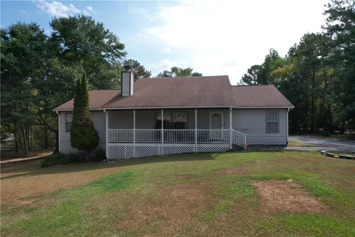 Front exterior with light-colored siding, a covered porch with white railings, and a prominent chimney