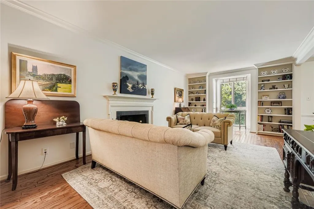 Living room featuring light wood-type flooring, crown molding, a fireplace, and built in shelves