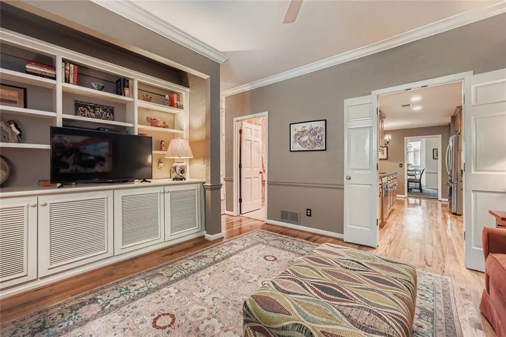 Living room with light wood-style flooring, crown molding, and ceiling fan
