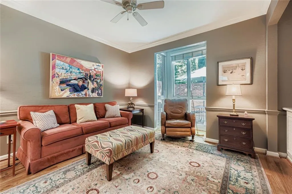 Living area featuring wood finished floors, ornamental molding, and a ceiling fan