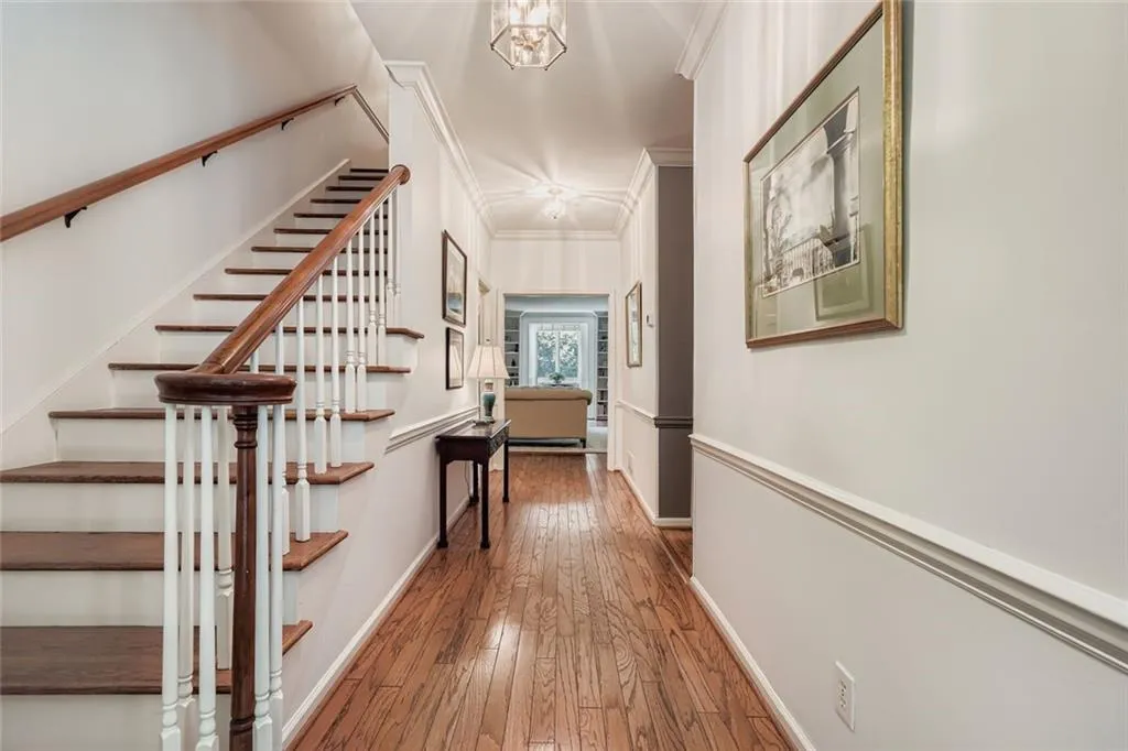 Hallway with ornamental molding, hardwood / wood-style floors, a chandelier, and stairs