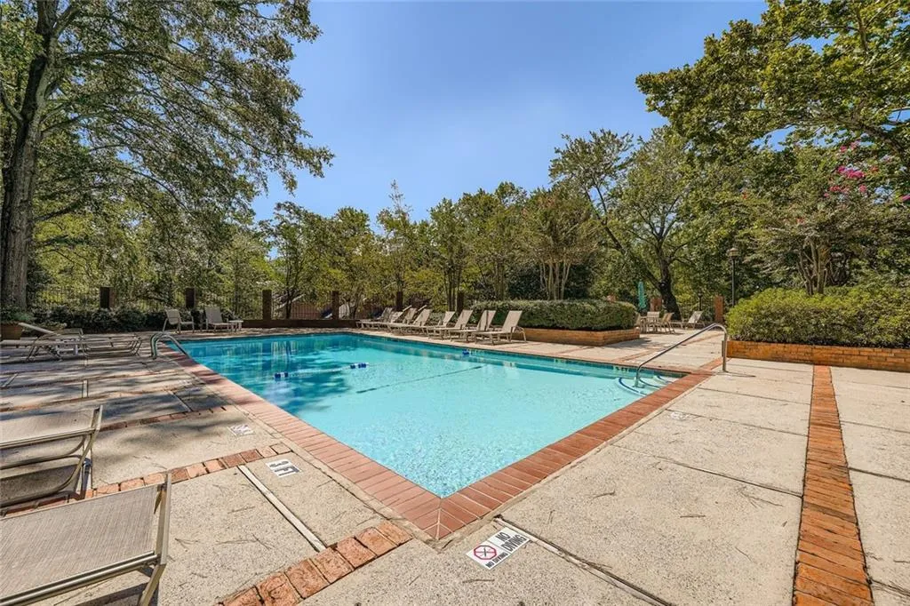Community pool with a patio and view of scattered trees