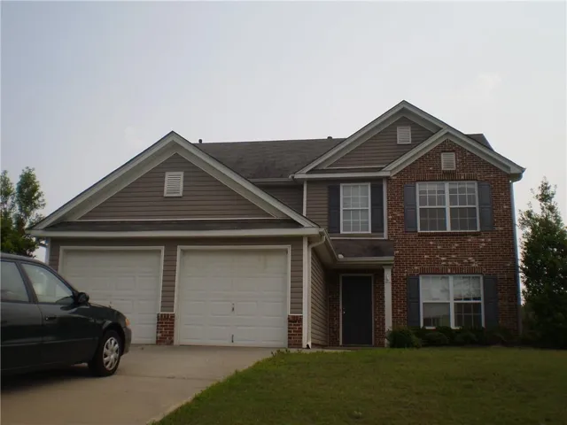 Two-story residence featuring a brick and siding exterior, two-car garage, front entry with transom window, and multiple windows with shutters