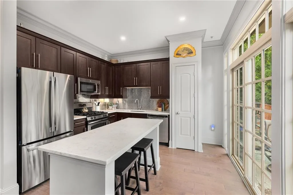 Kitchen featuring stainless steel appliances, dark brown cabinets, a breakfast bar, backsplash, and ornamental molding