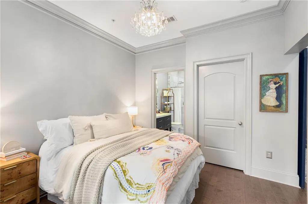 Bedroom featuring ornamental molding, a chandelier, ensuite bathroom, and dark wood-style floors