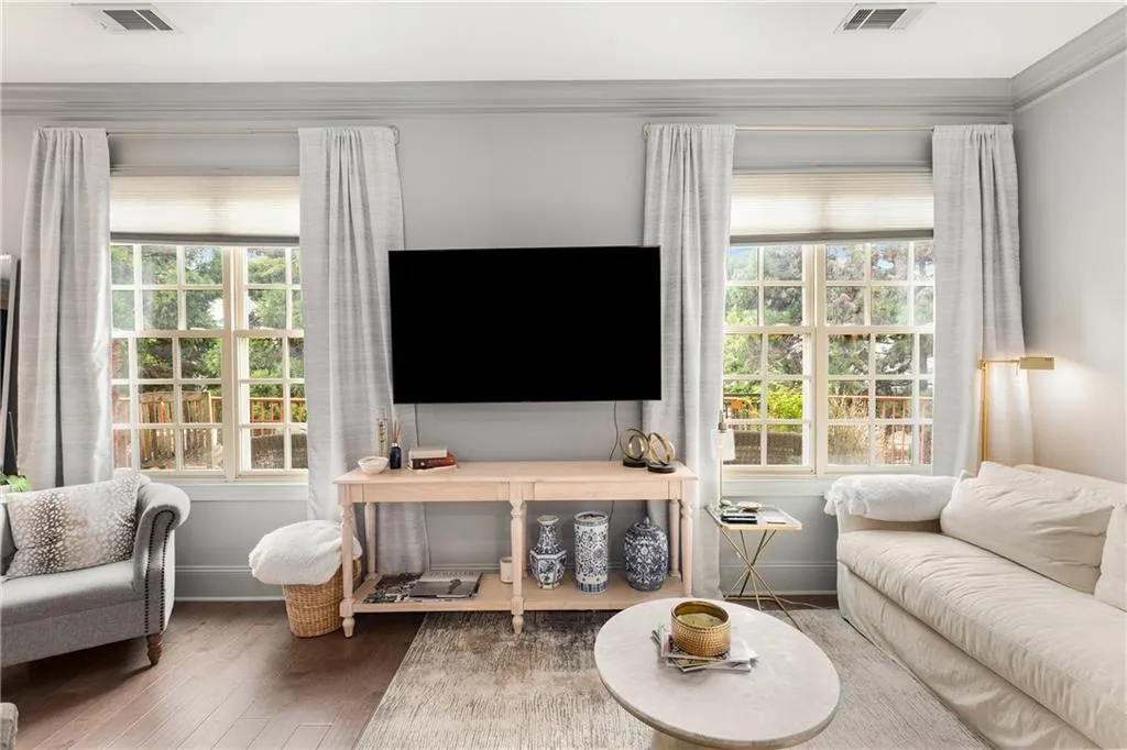 Living area featuring wood finished floors, healthy amount of natural light, and ornamental molding