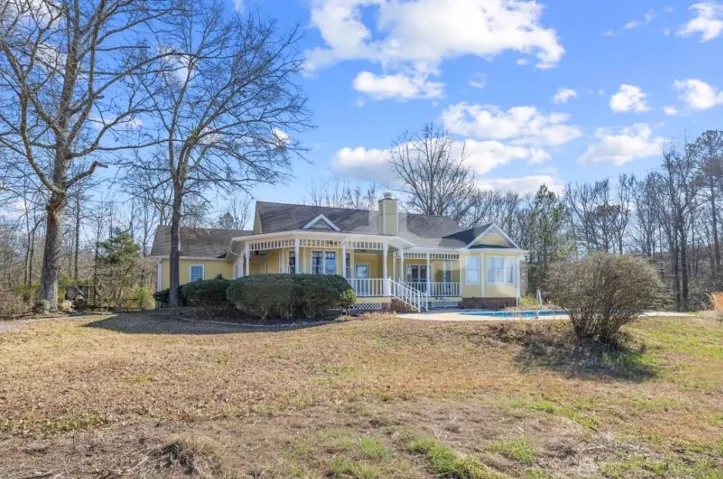 View of front of home featuring a chimney, a front lawn, an outdoor pool, and a porch