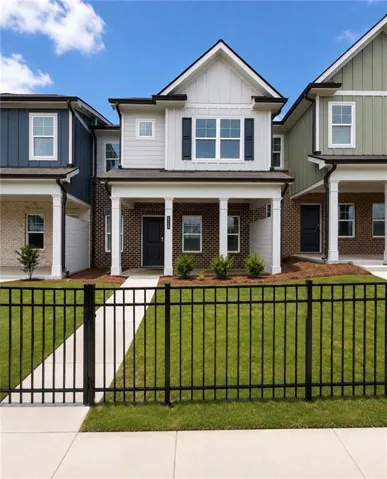 Contemporary townhome featuring a brick facade, white siding, and a covered front porch with white columns