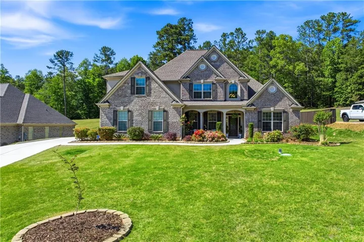 Traditional brick exterior featuring multiple gables, an inviting covered front porch, and mature landscaping