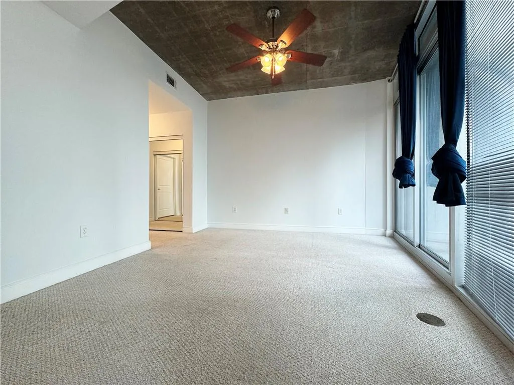 Carpeted spare room with a ceiling fan and baseboards