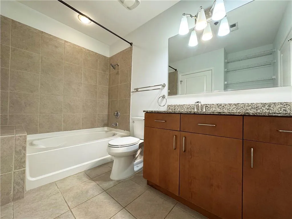 Bathroom with bathing tub / shower combination, vanity, and light tile patterned floors
