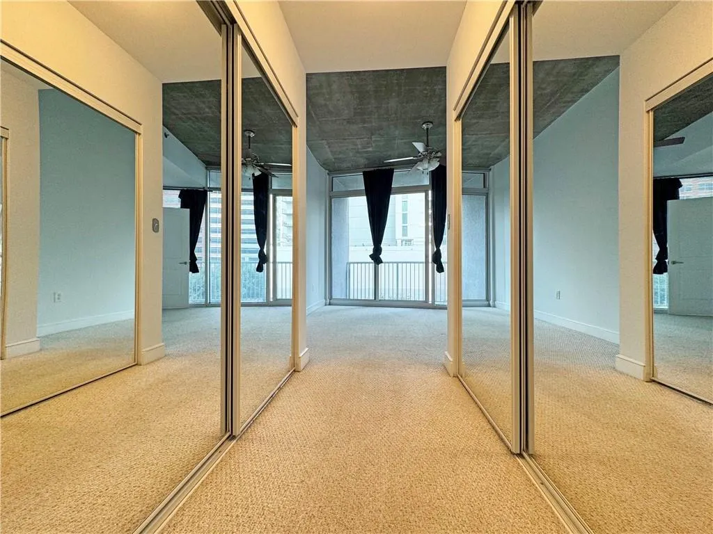 Below grade area featuring light carpet, plenty of natural light, and ceiling fan