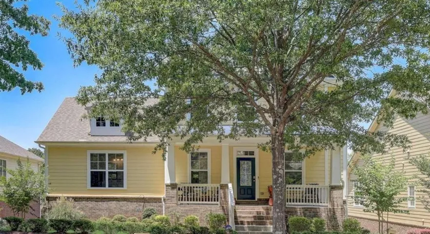 Yellow siding exterior featuring a covered front porch, white railings, and brick foundation