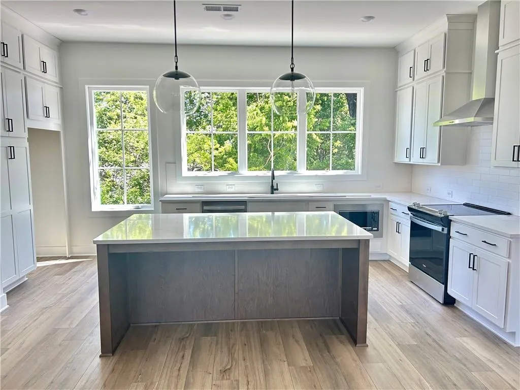 Plenty of countertop space in this kitchen with white cabinets and a stained island and oversized windows