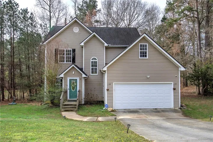 Traditional home featuring a front yard, driveway, a shingled roof, and an attached garage