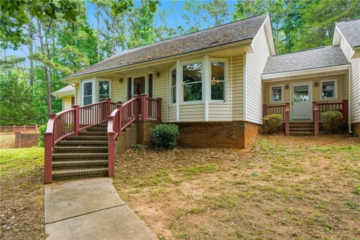 Exterior featuring horizontal siding, brick foundation, multiple bay windows, and a covered entry with a railing