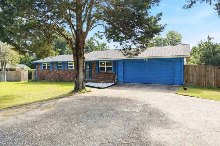 Brick exterior with blue shutters, attached two-car garage, established front tree, and a paved driveway