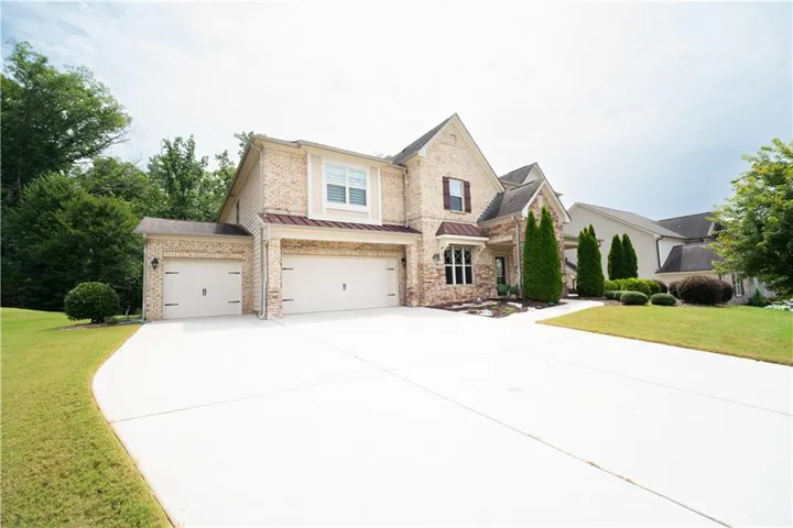 Expansive concrete driveway leading to a three-car garage