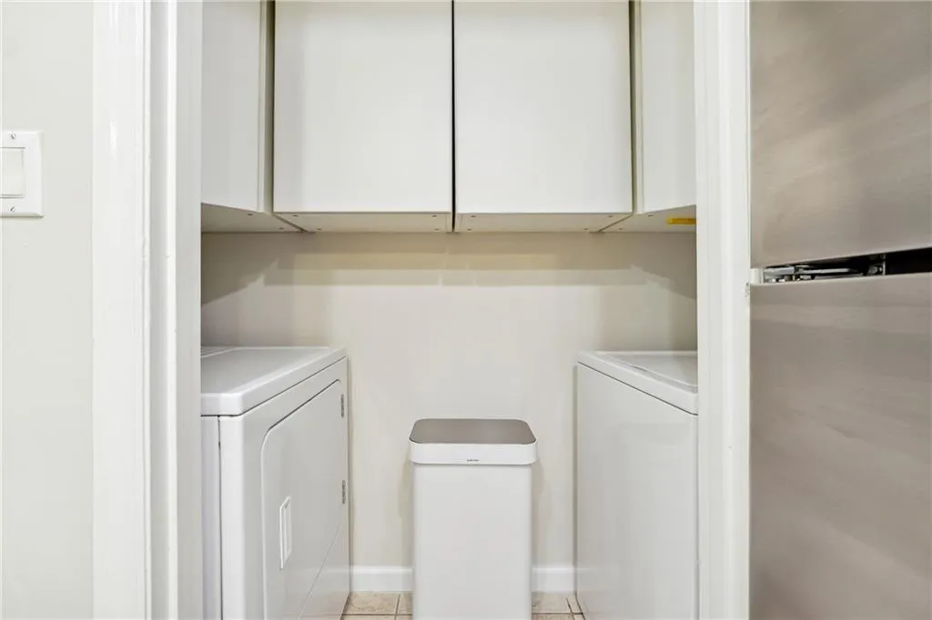 Laundry room with washer and clothes dryer and light tile patterned floors