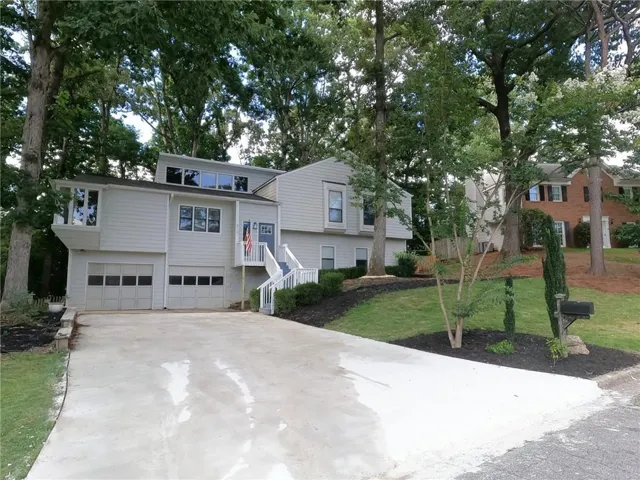 Split-level residence featuring a light gray exterior with a contrasting dark gray roof